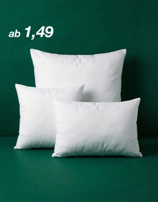 Drei weiße Kissen in unterschiedlichen Größen sind vor einem dunkelgrünen Hintergrund angeordnet. Links steht der Preis „ab 1,49“.